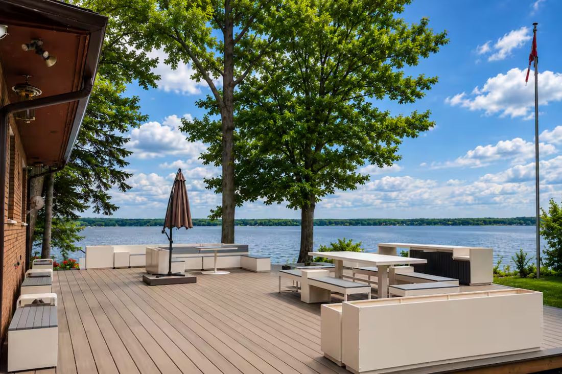 Wide lakeside deck with white outdoor seating