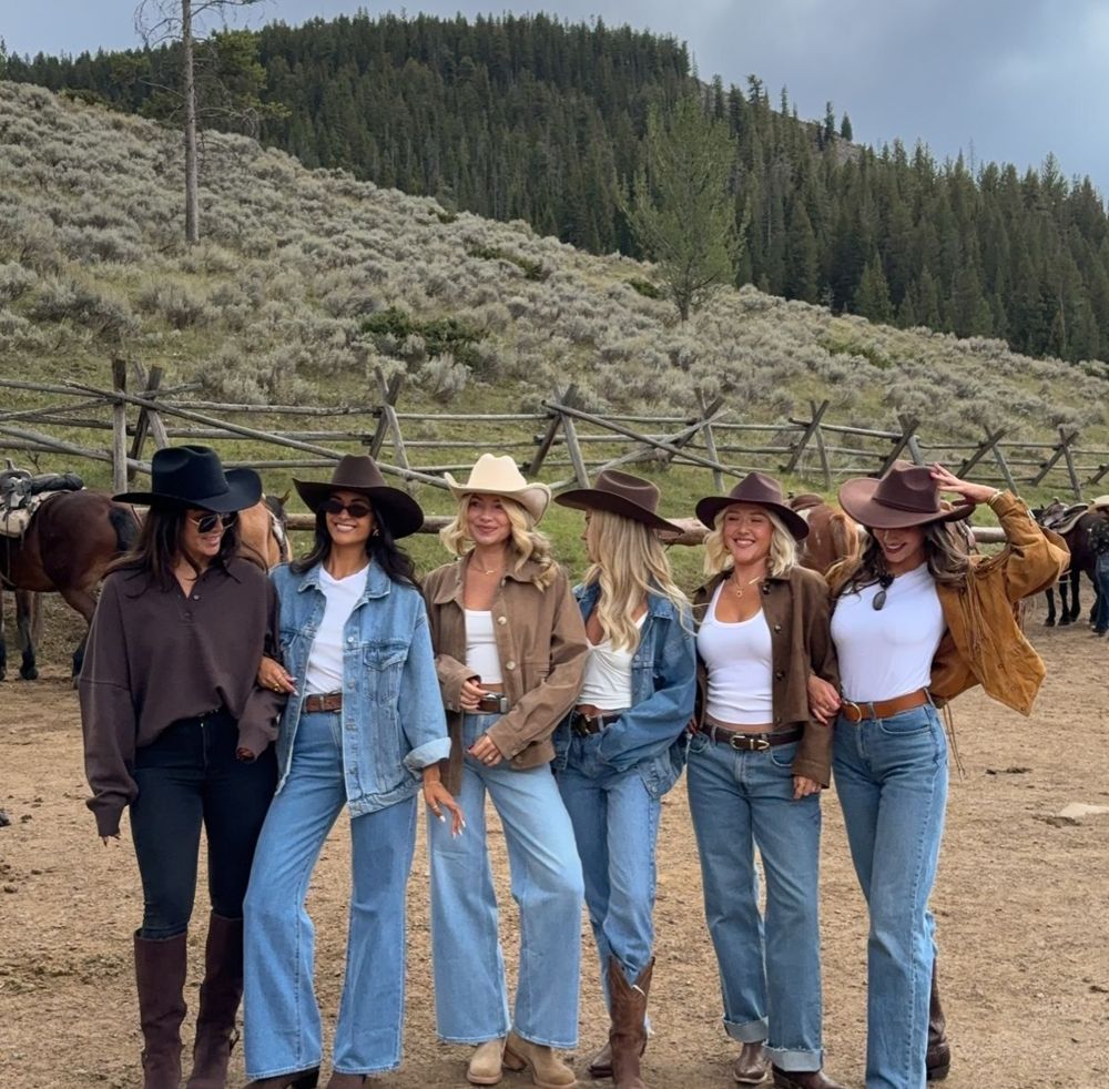 Group of women in cowboy hats, denim, suede jackets and boots at a ranch