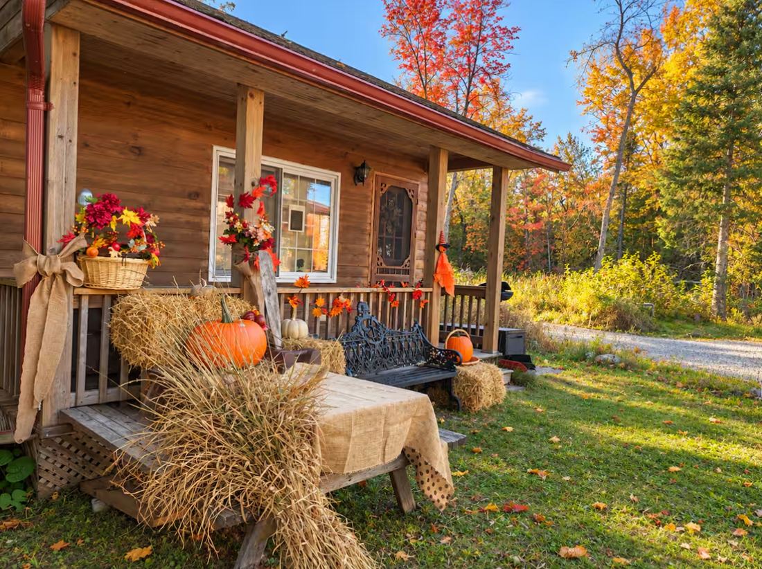 Log cabin porch decorated for fall with pumpkins and hay bales